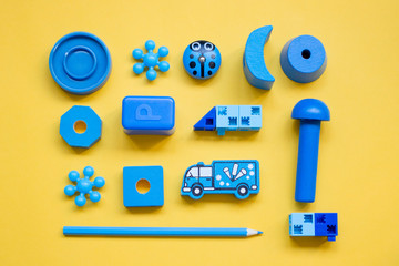 Moscow, Russia- 08 13 2018: blue children's toys, laid out in a pattern on a yellow background, top view