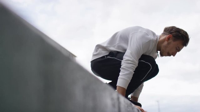 Young man doing a handstand at the edge of a wall, in slow motion 