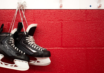 Hockey skates hanging in locker room with copy space in red background