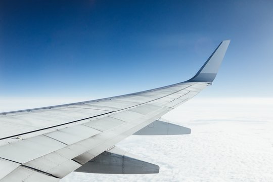 airplane wing against clouds and blue sky background