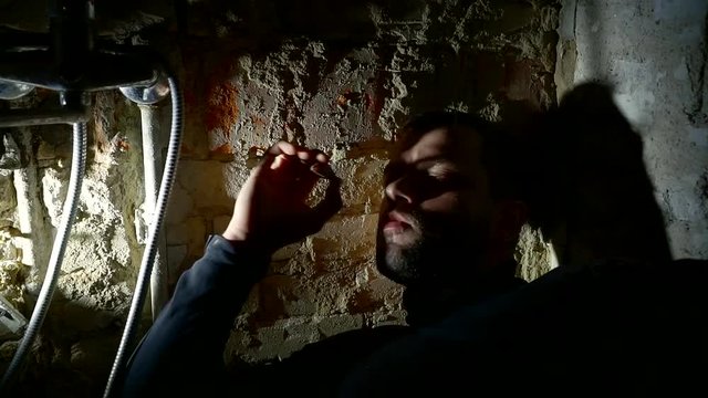 Portrait of a deeply depressed man lying in diry and smoking.