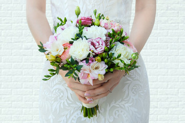 The bride is holding a bouquet of flowers in her hands. Close-up.