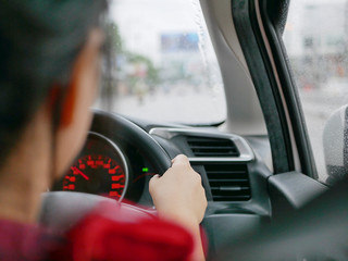 Asian woman's hand driving car in the rain