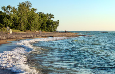 Deserted beach with lifeguard chairs and trees in background on Presque Isle on Lake Erie - obrazy, fototapety, plakaty