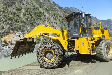 Excavator working on repairing a road ,heavy industry hydraullic with chain protect at front wheel ,new silk road National Highway 35 or China-Pakistan Friendship Highway.