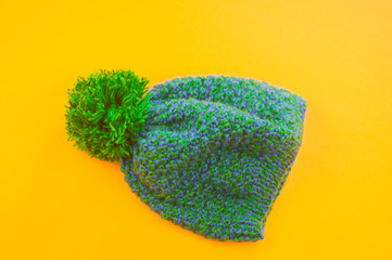 Green-blue cap of wool on a yellow background