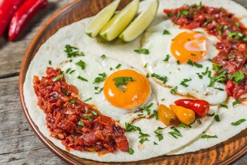 Mexican cuisine. Breakfast huevos rancheros on a wooden table