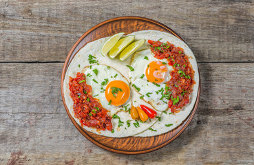 Mexican cuisine. Breakfast huevos rancheros on a wooden table. The view from the top. Copy-space.  