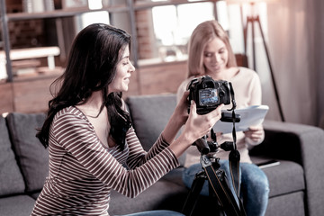 Our weekend. Inspired slim woman fixing her camcorder while her friend sitting in the background
