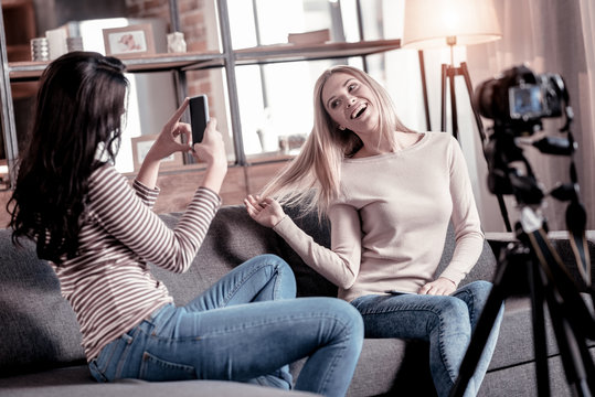 Great photos. Cheerful blond woman smiling while her friends photographing her