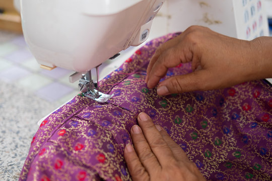 Woman sews strips of fabrics with sewing machine