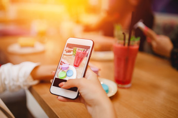 Young woman blogger is making mobile food photo. Concept content for instagram