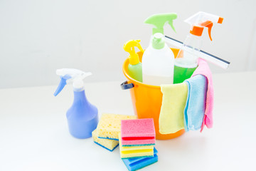 Bucket with cleaning supplies and tools on table