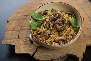 Bowl of pasta with cep boletus and champignons in a rustic wooden setting, studio shot