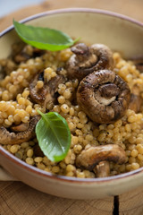 Close-up of pasta with roasted champignons and fresh green basil, selective focus, vertical shot