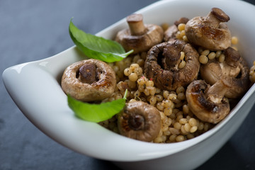 Italian pasta with fried champignons served in a white bowl, selective focus