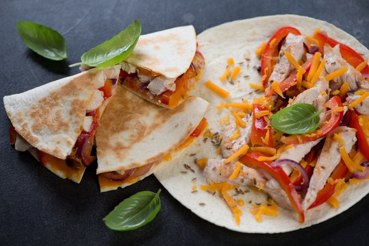 Closeup of quesadilla stuffed with grilled chicken meat, vegetables and cheddar, selective focus