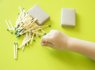 A small child plays with matches, a child's hand takes matches from the table, a close-up, a fire,...
