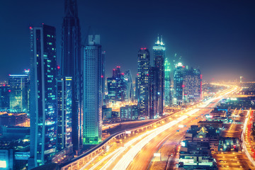 Fototapeta premium Malownicze nocne panoramę centrum Dubaju, Zjednoczone Emiraty Arabskie. Widok z lotu ptaka na autostrady i wieżowce w oddali.