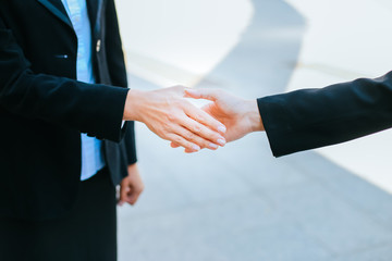 close-up of two business women shaking hands while standing two people greet each other in the city.