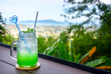 apple italian soda with mint leaf on wooden table with natural blur background, copy space