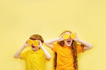 Laughing kids with orange eyes shows white healthy teeth on a yellow background.