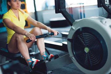 Rowing in the gym. Young woman training using rowing machine © Ulia Koltyrina