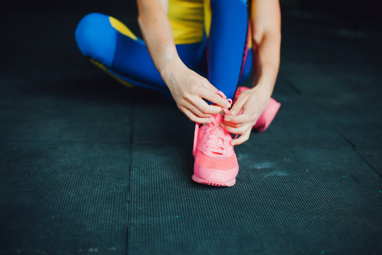 Girl in fitness club. Young female athlete sitting on floor and tied his shoelaces © Ulia Koltyrina