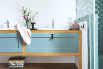Bathroom sink with blue drawers, pink towel and bouquet
