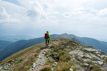 young tourist with a wooden stick walking on a mountain trail