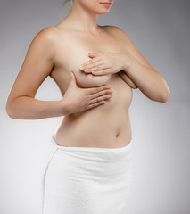 Woman examining breast isolated on gray  background 