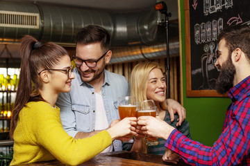 Group of four friends drinking beer and chat on lokal cafe