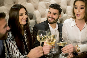 Group of young people celebrating and toasting with white wine