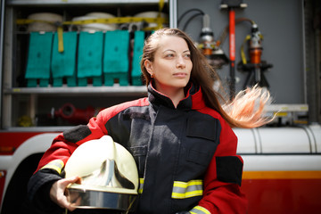 Photo of young woman with long hair looking to side next to fire engine