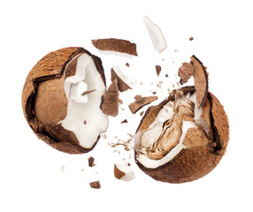 Coconut broken in the air into two halves on white background