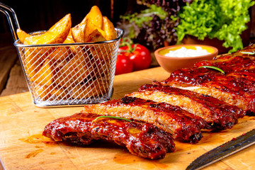 bbq spareribs on the plate with green salad and white sauce.