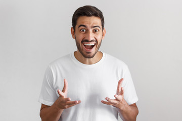 Crazy shocked young man in white t-shirt with wide opened mouth and bugged eyes, shouting Oh my...