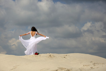 Piękna dziewczyna w białej sukni tańczy na szczycie piaszczystej wydmy, pustynia. - obrazy, fototapety, plakaty