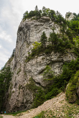 Two Tourists Walking By a Huge Rock in the Mountains