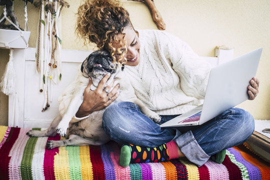 real best friends cheerful woman working at laptop on the terrace at home while hug her best love and friends  smiling dog pug sitting at his left. colorful and enjoyed concept image for couple
