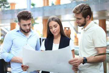 Group of young modern people in smart casual wear having a brainstorm meeting while standing in the creative office.