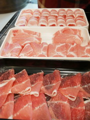 Selective focus of thin pork (top) and beef (bottom) slices ready to be cooked