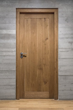 Modern quality wooden door in contemporary interior, Solid oak door with stainless steel handle set in concrete wall