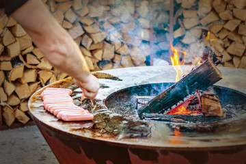 man frying sausages on a round grill