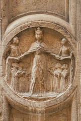 Virgin Mary between praying monks and angels, an ancient religious relief on a Venice wall