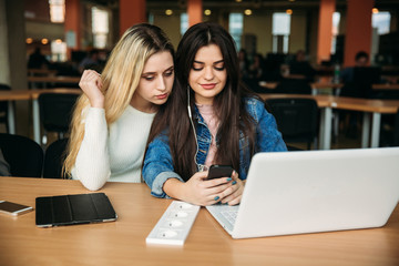 Two girl student use tablet and laptop in library. And listen music
