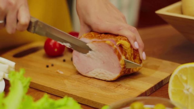 Cutting slice of ham on wooden board