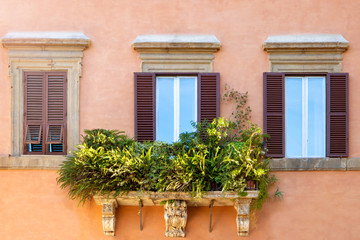 Fototapeta na wymiar Bright colorful facade of old European building with Windows, balconies and flowers in Rome, Italy. Laconic minimalist concept.
