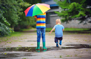 Children walking in wellies in puddle on rainy weather