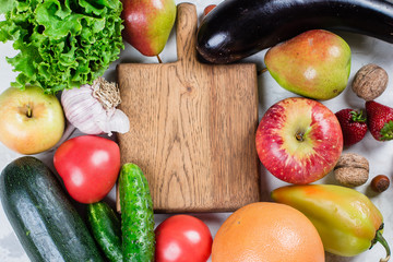 Empty wooden board with place for recipe. Healthy food fruits and vegetables on a white table. Top view. Flat lay.